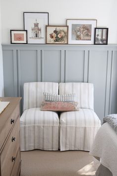 a white couch sitting next to a wooden dresser in a room with pictures on the wall