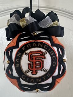 a san francisco giants ornament hanging from a door with black and orange ribbon