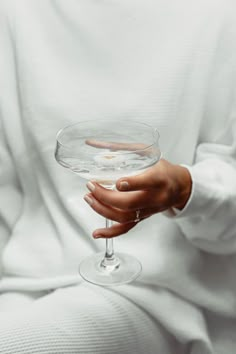 a person holding a wine glass in their left hand and wearing a ring on her finger