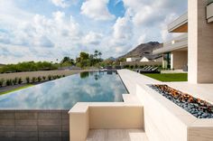 an outdoor swimming pool with stone steps leading up to it and mountains in the background