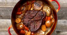 a pot filled with meat and vegetables on top of a wooden table