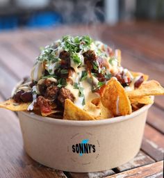 a bowl filled with nachos sitting on top of a wooden table