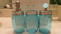 three blue mason jars sitting on top of a bathroom counter next to a faucet