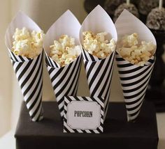 four black and white striped paper cones with popcorn in them sitting on top of a table