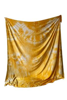 a yellow and white tie dyed fabric hanging on a wall in front of a white background