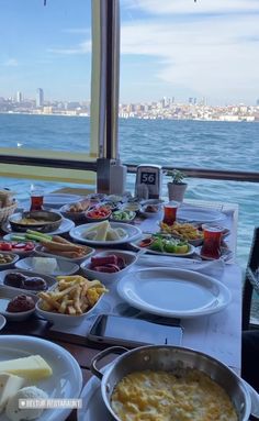 a table full of food with the ocean in the background