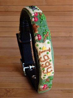 a dog collar with an embroidered name and pictures on the collar is sitting on a wooden surface