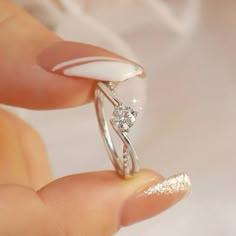 a woman's hand holding a ring with a diamond on the top and side