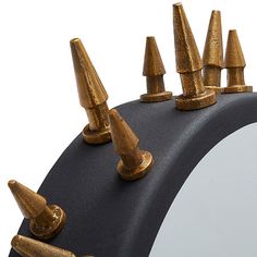 a mirror with gold spikes on top of it