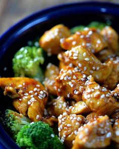 a blue bowl filled with chicken and broccoli covered in sesame seed flakes