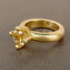 a yellow gold ring with an oval cut diamond in the center, sitting on a table