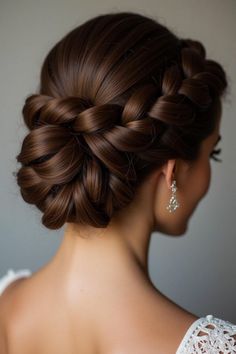 a woman with long brown hair in a braid updo and earrings on her head