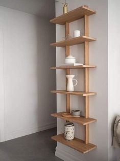 a wooden shelf with some cups and vases on it's sides in a room