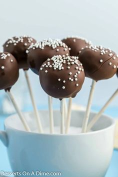 chocolate cake pops with white sprinkles in a cup on a blue table