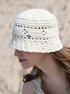 a woman wearing a white crocheted hat on the beach