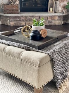 a living room with a couch, coffee table and fireplace in the background that has a potted plant on it