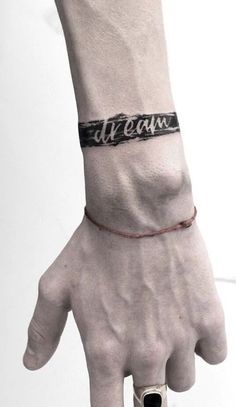 a hand with a wristband that says dream on it and an arrow in the middle