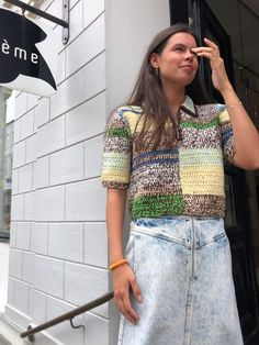 a woman standing in front of a building talking on a cell phone