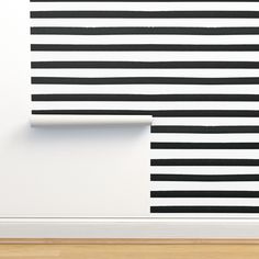 an empty room with black and white stripes on the wall, next to a wooden floor