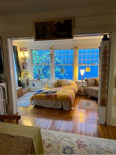 a bedroom with hardwood floors and large windows