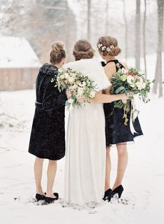 three bridesmaids standing in the snow with their bouquets wrapped around each other