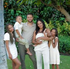 a family poses for a photo in front of a palm tree with their two children