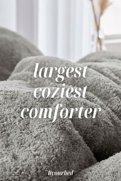 the words largest coziest comforter are in white lettering on a gray bed