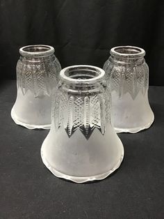 two clear glass vases sitting next to each other on a black tableclothed surface