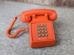 an orange telephone sitting on the ground