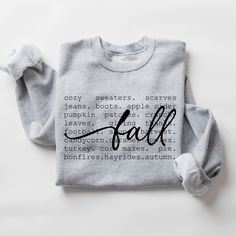 Fall Cozy Sweatshirt Sizes: Small- 3XLarge Embrace the warmth and coziness of the season with our Cozy Fall Words Sweatshirt Featuring a collection of your favorite fall-inspired words, this sweatshirt brings the essence of autumn right to your wardrobe. Crafted with a soft, plush interior and a classic fit, it's perfect for chilly days, whether you're lounging at home or enjoying the crisp outdoor air. Available in multiple colors, this fall essential pairs effortlessly with leggings or jeans for a comfy, laid-back look Everyday Gray Sweatshirt For Fall, Casual Sweater With Graphic Print For Fall, Gray Sweater With Graphic Print For Fall, Gray Crew Neck Sweatshirt For Fall, Gray Cotton Sweater For Fall, Cotton Sweater For Fall, Comfy Gray Tops For Fall, Fall Sweatshirt With Lettering And Long Sleeves, Fall Long Sleeve Sweatshirt With Lettering