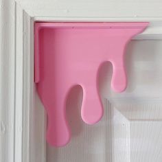 a pink wall hanging on the side of a door with a dripping paint drop in it