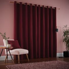 a living room with pink walls and wooden flooring is shown in front of a red curtain