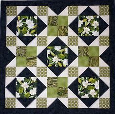 a green and black quilt with white flowers on the center is featured in this image