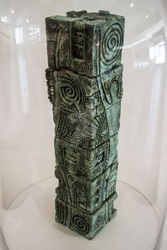 a green vase sitting on top of a glass display case