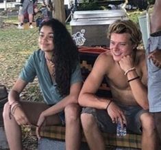 two young people sitting on a bench in the park, one is holding a water bottle