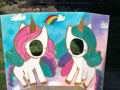 a cardboard box with two unicorns painted on the front and sides, sitting in grass