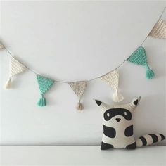 a stuffed raccoon sitting on top of a table next to a string of tassels