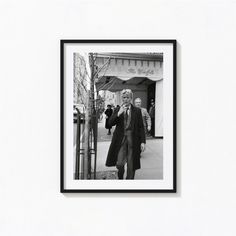 a black and white photo of a man walking down the street