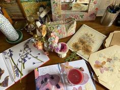 an open book sitting on top of a wooden table next to flowers and vases