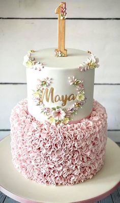 a pink and white cake with a one on top that has flowers all over it