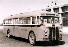 an old bus is parked in front of a building with large windows and no doors