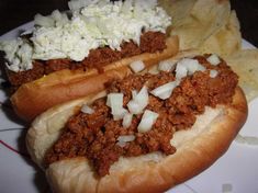 two chili dogs with onions and cheese on a plate