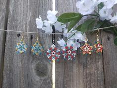 some beads are hanging on a clothes line next to white flowers and green leaves in front of a wooden fence