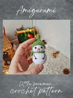 a hand holding a small crocheted snowman ornament in front of a christmas tree