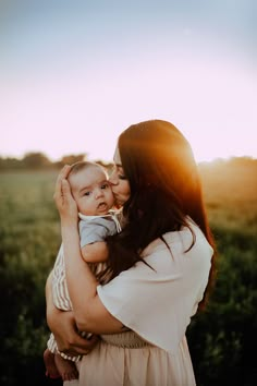 a woman holding a baby in her arms while the sun shines down on them