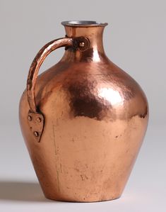 a large metal vase with a handle on it