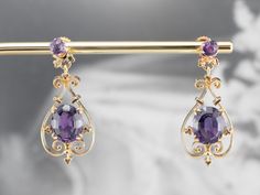 These vintage amethyst drop earrings are a beautiful example of Victorian Revival jewelry! Scrolling filigree and dimensional accents give these earrings an ornate look that pairs well with the royal purple amethysts, original to the piece. Stud findings keep these earrings secure and comfortable when worn. Metal: 14K Yellow Gold Gem: 4 Amethysts Gem Measurements: 9 x 12 mm, Oval (Largest) Earrings Length: 39 mm Earrings Width: 17 mm Marks: "14K" Stamped on the Findings Gold And Purple Bracelet, Purple Earrings Aesthetic, Vintage Drop Earrings, Victorian Revival, Purple Gems, Purple Bracelet, Gothic Accessories, Purple Jewelry, Amethyst Gem