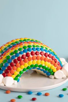 a rainbow cake with white frosting and sprinkles on a blue background