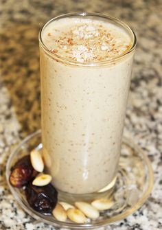 a glass filled with milk and nuts sitting on top of a marble counter next to a plate