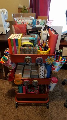 a red cart filled with lots of school supplies on top of a carpeted floor